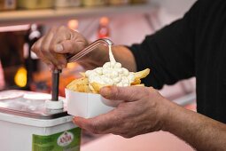 Mayonnaise über Pommes frites geben (Brüssel, Belgien)