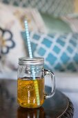 Yellow drink in mason jar with handle and drinking straw