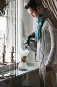 Young man wearing scarf making filter coffee