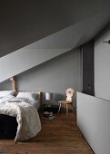 Grey walls and ceiling in attic bedroom with sloping ceiling and dormer window