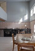 Gallery and kitchen-dining area in double-height interior of old, renovated wooden house
