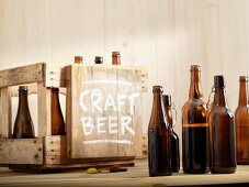 Geöffnete Bierflaschen und Holzkiste mit Aufschrift 'Craft Beer'