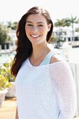 A young brunette woman wearing a knitted top and a thin jumper