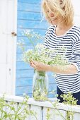 Frau im Streifenshirt arrangiert Blumen in einem Einmachglas