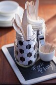 Wooden cutlery and football-patterned napkin in glass jar