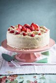 A white chocolate and strawberry cake on a cake stand