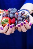 Hands holding fresh berries and grapes