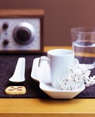 White china crockery and biscuit on dark felt mat