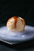 Caramel and hazelnut butter ice cream with caramel sauce on an ice plate