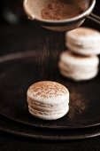 Gluten-free macarons being sprinkled with cinnamon