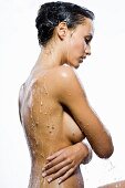 Frau mit nacktem Oberkörper unter Wasserstrahl