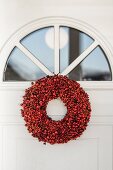 Roter Beerenkranz an einer Haustür mit halbrundem Fenster