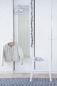 Lady's jacket hung from clothes hanger and step stool in front of white wardrobes