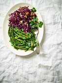 Green vegetables with clover and a red cabbage salad with pecan nuts for St. Patrick's Day