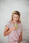 A woman drinking a green smoothie
