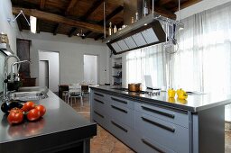 Modern island counter in kitchen of renovated country house with rustic wood-beamed ceiling