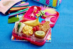 Snack box with banana, kiwi, vegetable muffin, sandwich and raspberries