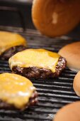 A hamburger with melting cheese on a grill