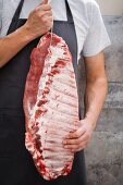 A butcher holding raw spare ribs