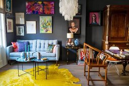 Wohnzimmer mit Möbeln im Stilmix und Bildern an grauer Wand