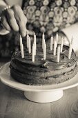 A chocolate cake being decorated with birthday candles