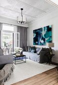 Gray couch set against a modern picture in the living room with stucco ceiling