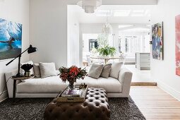 Upholstered table with brown leather upholstery and light couch in an open living room