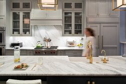 Frau geht durch luxuriöse Küche mit Arbeitsplatte aus Marmor