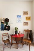 Folding table, two wooden chairs, vintage posters on wall and collection of hats on coat pegs