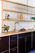 Kitchenette with black fronts and shelves on wall with glasses