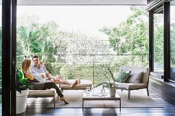 Elegantly furnished loggia with a couple on a filigree outdoor sofa, two-seater and coffee table