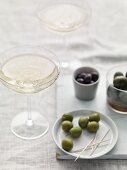 Different types of olive with toothpicks and champagne glasses