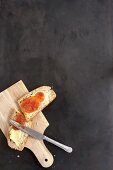 Eine Scheibe selbstgebackenes Hefebrot mit Butter und Marmelade