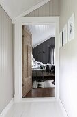 Narrow hallway with wood-clad walls and view into attic bedroom through open door