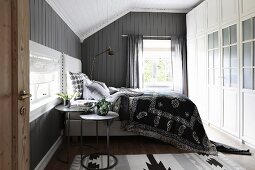 Box-spring bed in rustic bedroom with grey-painted wooden walls