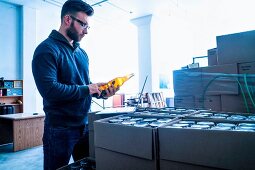 A man checking labels on beer bottles in a storage room (USA)