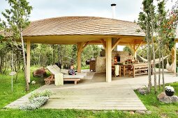 Comfortable sun loungers, dining area and pizza oven under large pavilion