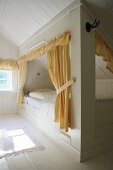 Yellow curtains and pelmets on cubby beds in wood-clad attic bedroom