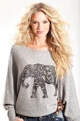 A young blonde woman wearing a knitted jumper with an elephant print