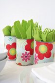 Tin cans covered with floral paper used as cutlery holders