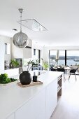 White island counter and spherical lamp in open-plan living area with view of countryside