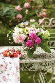 Romantic bouquet and fresh strawberries on vintage metal table in garden