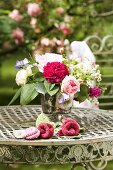 Romantischer Blumenstrauss und Strickblüten auf rundem Vintage Metalltisch im Garten