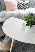 Weisser Couchtisch mit Blumenvase und Sofa mit kariertem Bezug