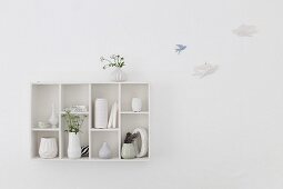 Collection of vases in wall-mounted display case next to bird ornaments mounted on wall