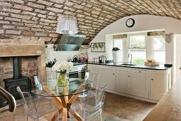 Elegante Landhausküche mit rustikaler Gewölbedecke, Designermöbeln und traditionellem Kaminofen