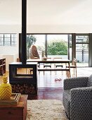 View through cosy living area with wood-burning stove to dining area and open terrace doors