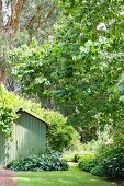 Gartenanlage mit grünen Büschen, Bäumen und grünem Gartenhaus