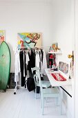 Colourful comic-style artwork above clothing rail holding black and white clothing in hipster-style period apartment