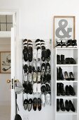 Shoes on shelves and wire rack behind white interior door in period apartment